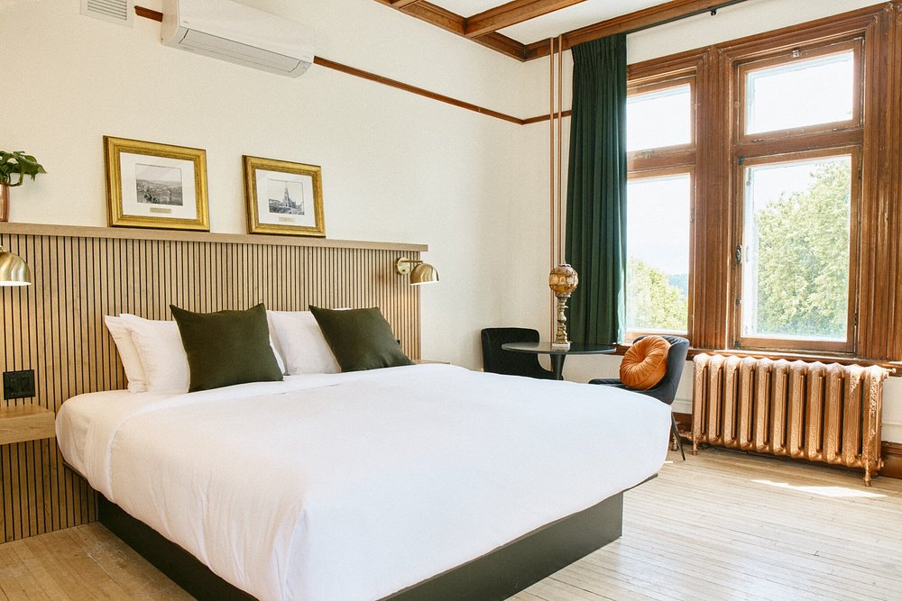 Helles Hotelzimmer mit historischen Möbeln und Blick ins Grüne